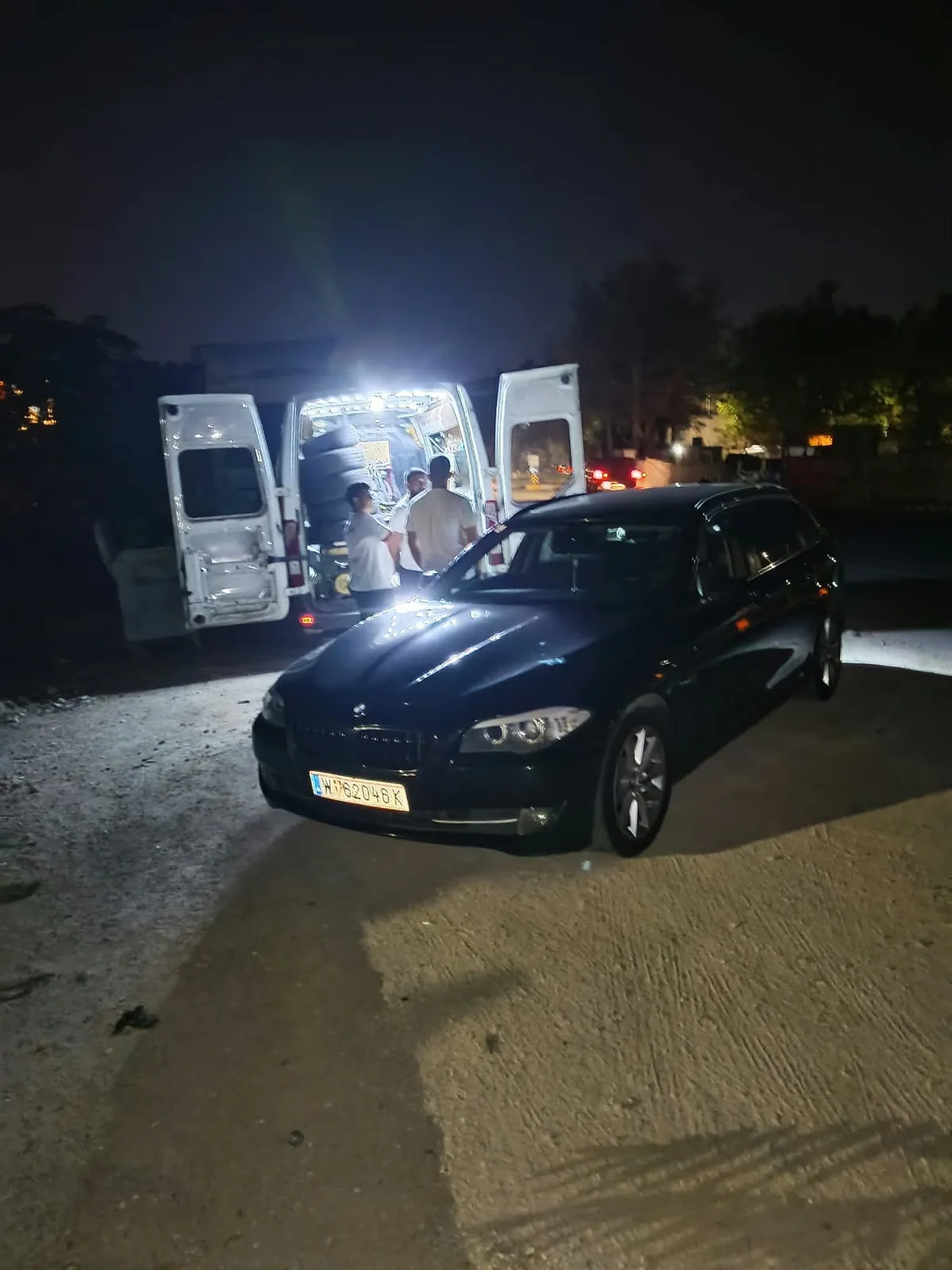 Gece servis aracının açık kapıları ve aydınlatması altında bekleyen araç